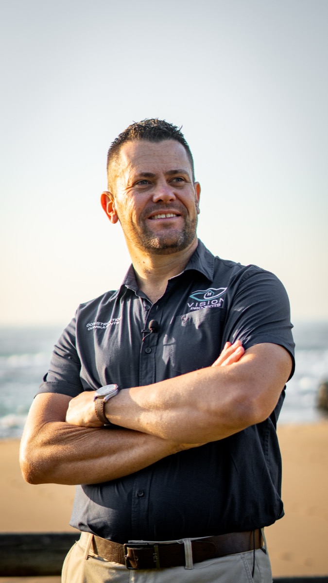 A smiling man, identified as a consultant, wearing a collared shirt and lapel microphone, representing business coaching and website concepts.
