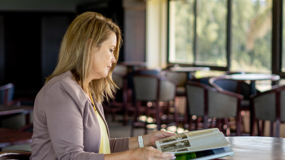 A woman intently looking at old black and white photographs in a book, representing design language, visual systems, and UI/UX philosophy.