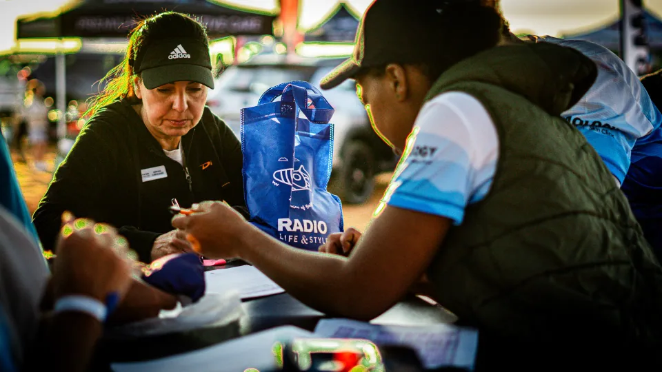 People talking at an outdoor event registration table.
