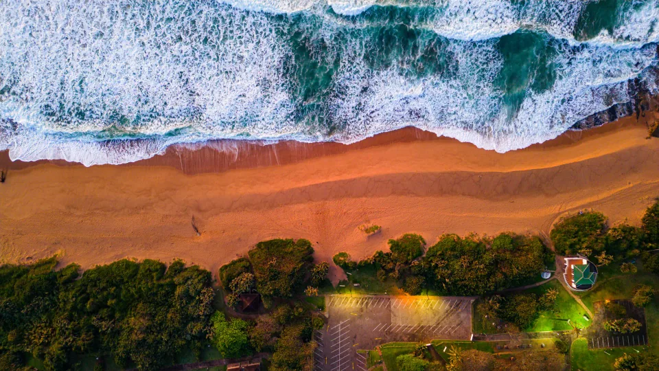 Waves breaking along a beach beside a coastal property.