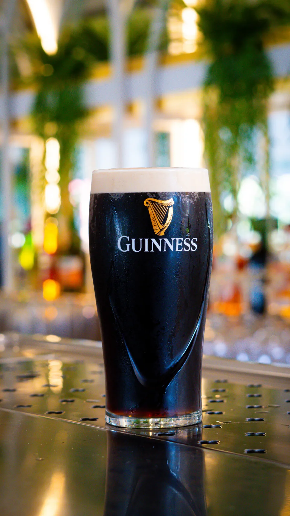A glass of stout on a bar counter.