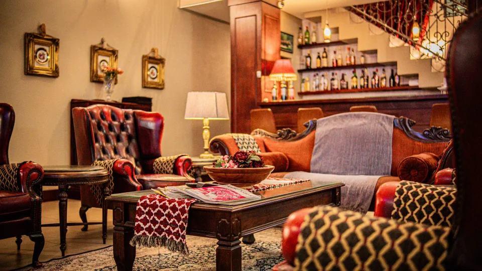 A warmly lit lounge with patterned armchairs and a bar.