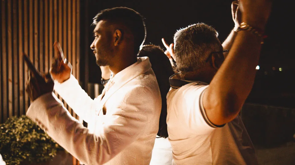 Two guests in warm light at an evening event.